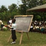 ghanaian child stood at chalkboar